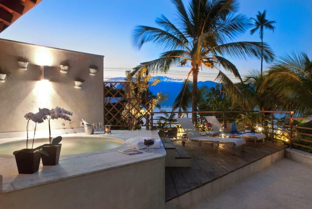 Deck do Abayomi Hotel com uma banheira de hidromassagem ao ar livre com vista para o mar e algumas espreguiçadeiras ao redor