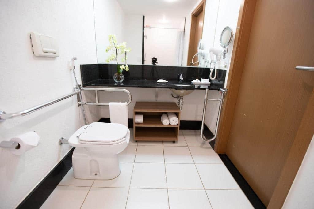 Banheiro adaptado do Athos Bulcão Hplus Executive com barras de apoio ao redor do vaso sanitário e perto da pia que é mais baixa também