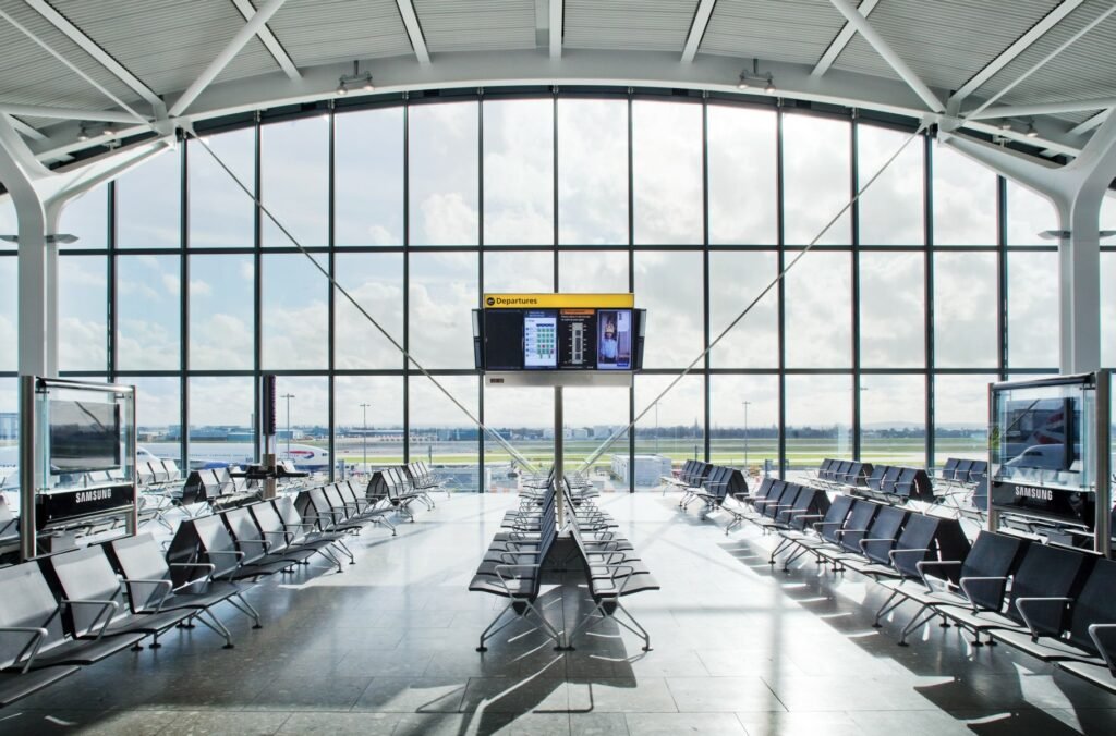 Saguão amplo do Aeroporto de londres Heathrow com uma janela enorme dando vista para a área de pouso dos aviões