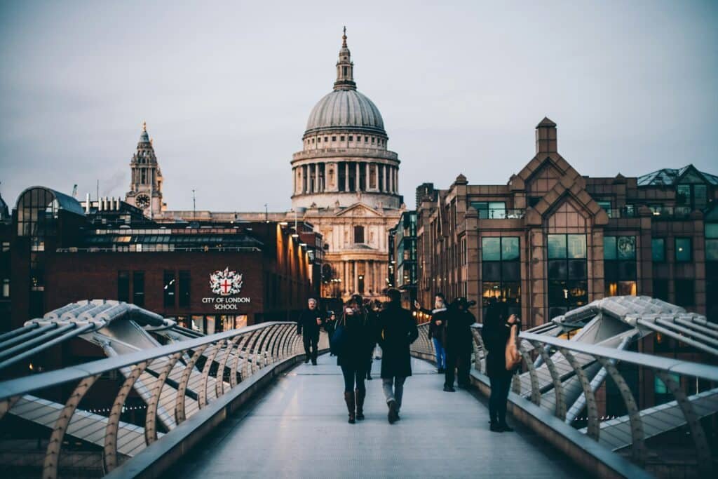 Pessoas caminhando na Millennium Bridge em Londres ao anoitecer, com a Catedral de São Paulo bem visível ao fundo para ilustrar o post de roteiro para Londres.