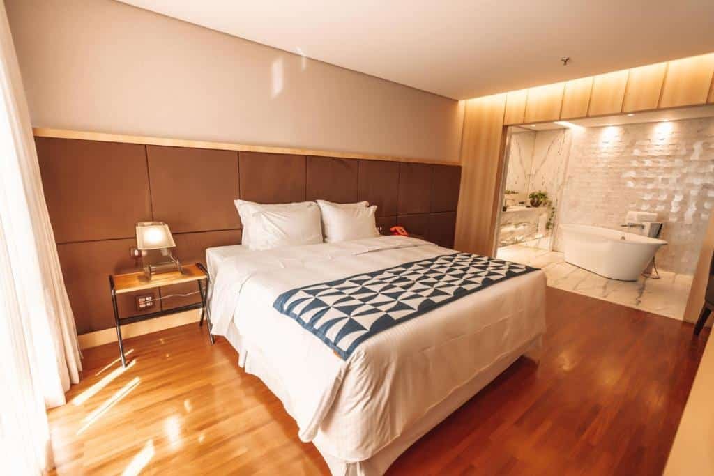 Quarto do Brasília Palace Hotel com dois ambientes, um está a cama de casal e no outro um banheiro espaçoso com uma banheira, para representar os hotéis perto do consulado americano em Brasília