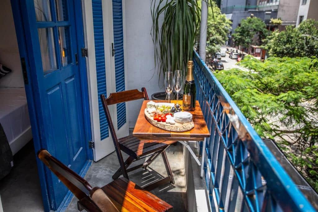 Uma mesa com duas cadeiras na sacada do quarto. Na mesa uma tábua de frios e um champanhe.