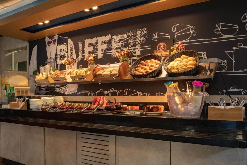 Mesa do café da manhã. Com uma prateleira em cima. Diversos pães, frios e sucos. Foto para ilustrar post sobre Hotéis perto do Hospital Sírio Libanês.