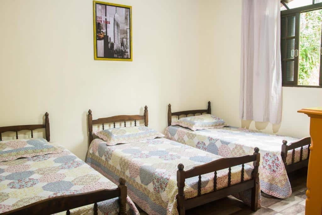 Quarto do Cantinho na roca 2. Três camas de solteiro, uma do lado da outra. Do lado direito uma janela. Foto para ilustrar post sobre airbnb em Santo Antônio do Pinhal.