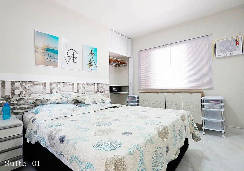 Quarto da Casa Sossego. Do lado direito uma cama de casal com uma cômoda. no fundo um pequeno guarda-roupa. Uma janela em cima de uma cômoda e um ar-condicionado do lado direito. Foto para ilustrar post sobre airbnb na Praia da Enseada.