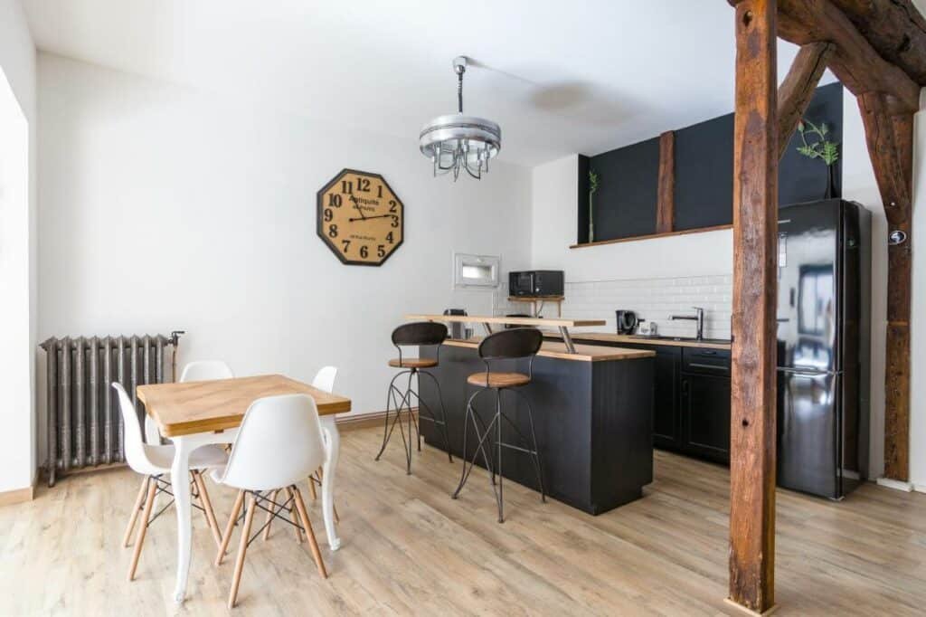 Cozinha do La Parenthèse com mesa de quatro lugares do lado esquerdo da imagem, do lado direito um balcão de madeira e ao fundo uma cozinha compacta com armário e geladeira. Representa hotéis no Vale do Loire.