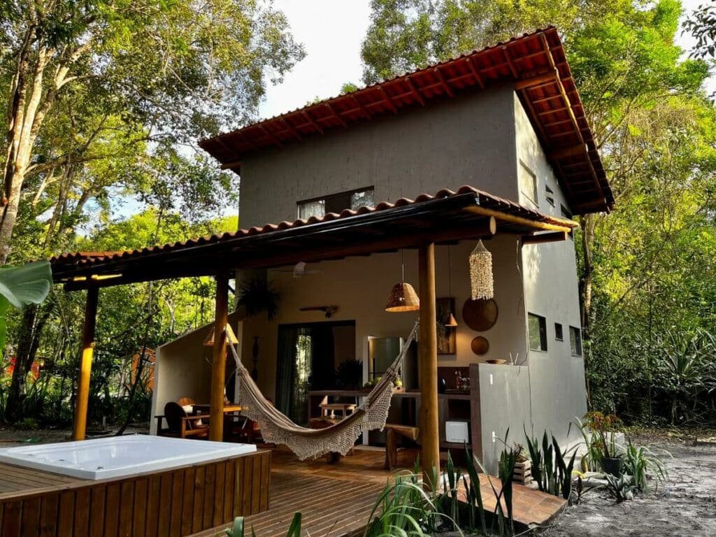 Frente da Casa Viva Trancoso durante o dia com uma banheira de hidromassagem a frente e ao fundo a estadia.