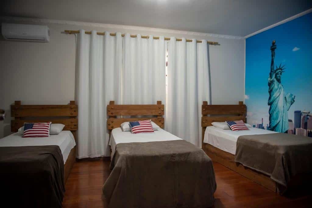 Quarto do Hotel Alvorada do Sol. Três camas de solteiro, no fundo uma janela com cortina. No canto esquerdo um ar-condicionado. Imagem para ilustrar post sobre hotéis perto do Expo Center Norte.
