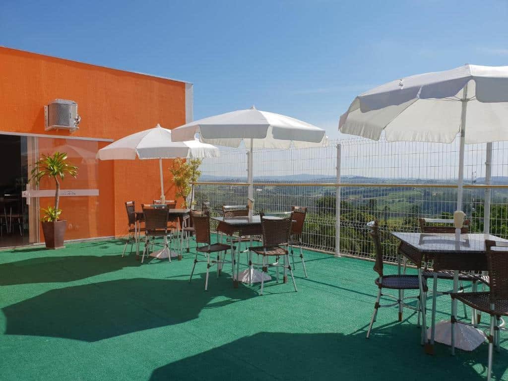 Cobertura do Hotel Itupeva Terrace Residence SPA com vista para algumas montanhas, no local há cadeiras, mesas e alguns guarda-sóis, para representar hotéis perto do Hopi Hari