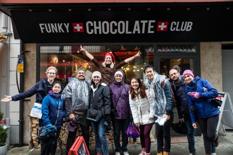Vários amigos posando para uma foto tirada em um city tour por Interlaken. Estão na frente da loja Funky Chocolate Club.