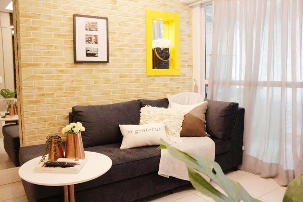 Sala de estar do LIV INN Apartamento na Beira-Mar Fortaleza. Um sofá está encostado em uma parede e ao lado da porta de uma varanda com cortina. Perto do sofá está uma mesinha.