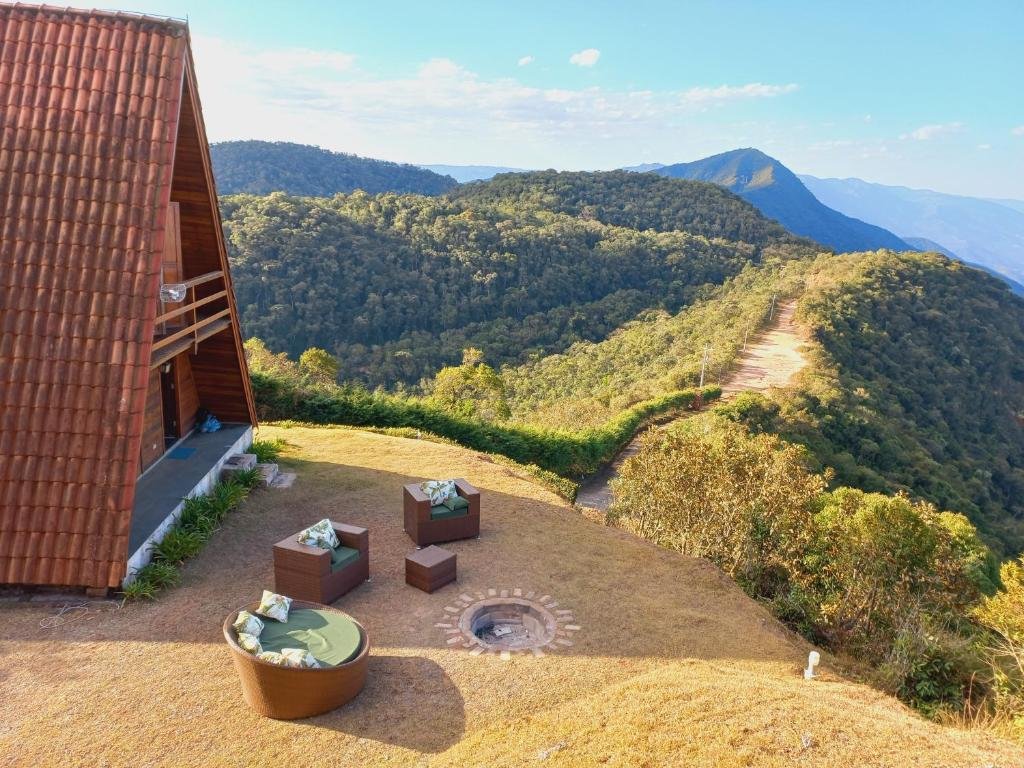 Área externa do Mirante 45. Do lado direito as montanhas, no meio uma lareira de chão, ao redor sofás. No lado esquerdo o chalé.