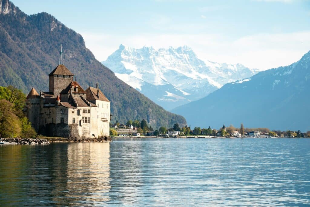 Imagem da cidade de Montreux  durante o dia com rio do lado direito e do lado esquerdo um castelo. Representa o que fazer na Suíça.
