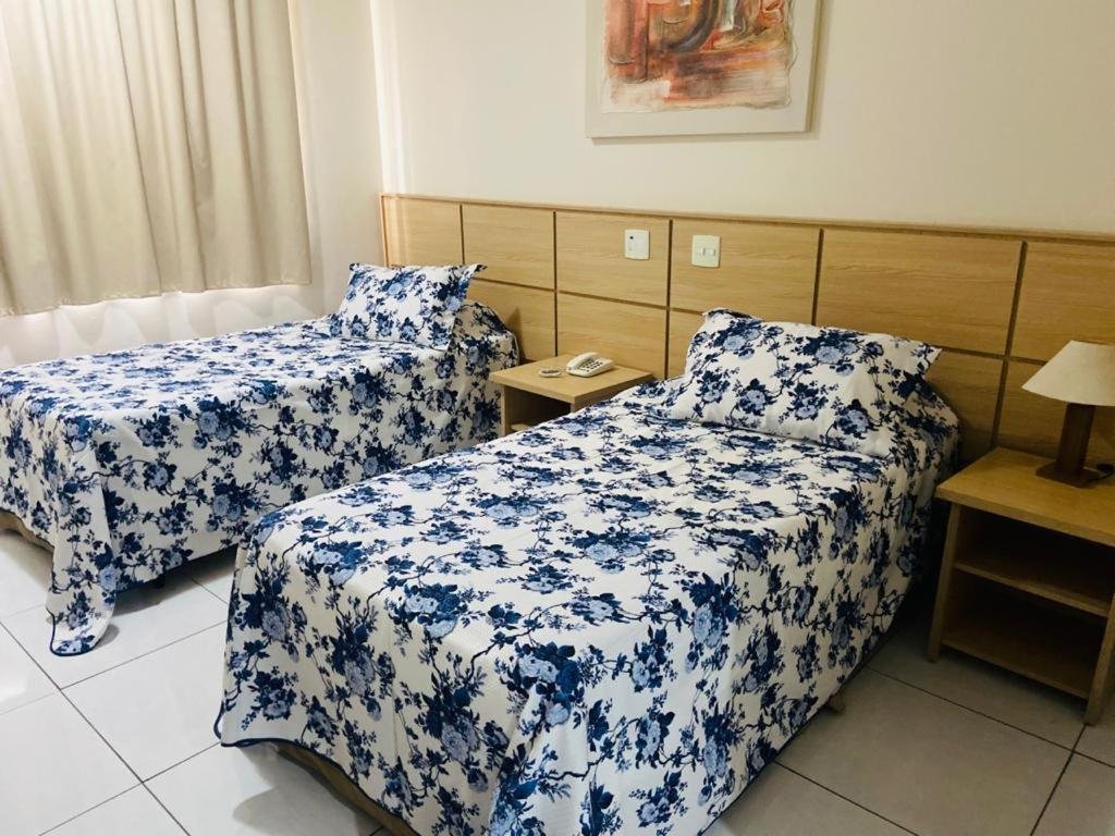 Quarto do Nacional Inn Campinas Trevo com uma janela com cortinas, duas camas de solteiro, duas pequenas mesinhas de cabeceira com abajures