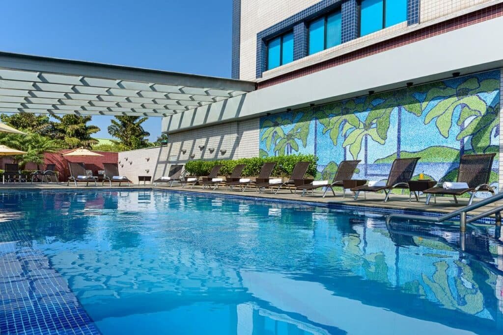 Piscina ao ar livre do Novotel Sao Paulo Center Norte. No fundo cadeiras de descanso.