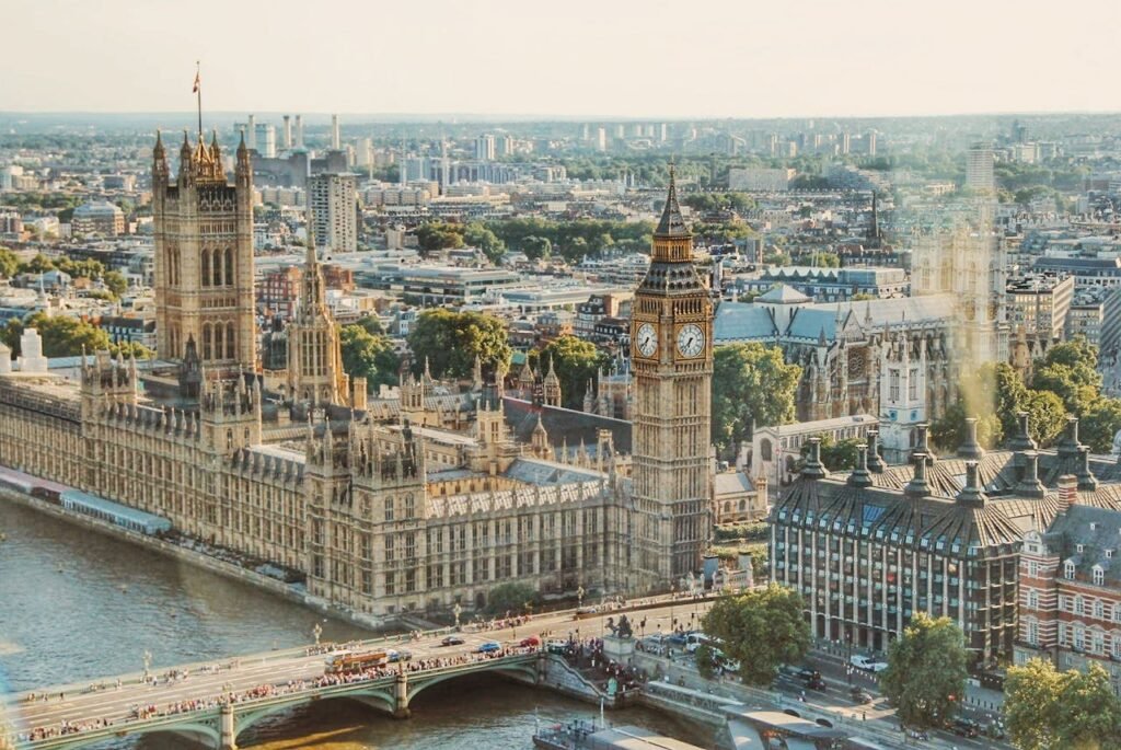 Vista aérea do Palácio de Westminster, às margens do Rio Tâmisa, com a Torre Elizabeth e o horizonte de Londres para ilustrar o post sobre roteiro em Londres.