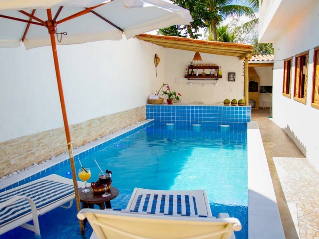 Piscina da Casa Viana Trancoso durante o dia com duas cadeiras a frente com vista para a pisicna.