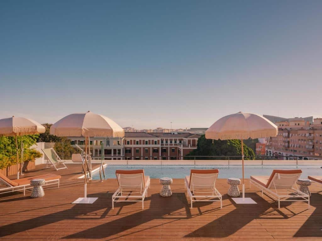 Piscina com borda infinita do Ibis Styles Sevilla City Santa Justa. Ao redor cadeiras de sol e guarda-sol, com a vista para a cidade.