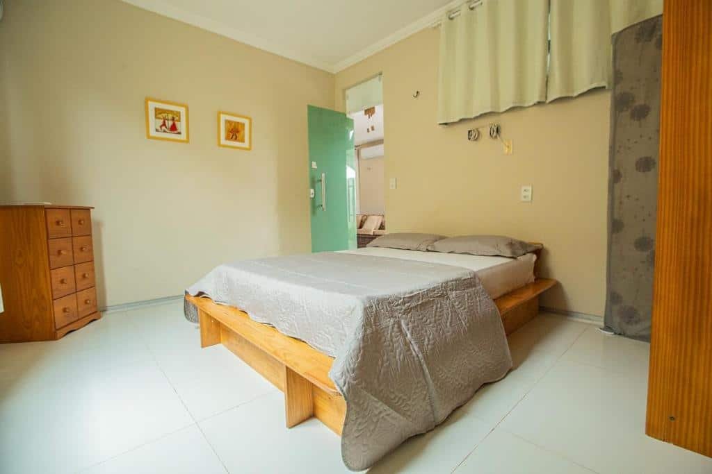 Quarto da casa Porto das Dunas Casa Temporada Estilo e Conforto. Uma cama de casal está no meio do ambiente, ao lado da porta. Na sua diagonal há uma cômoda. Este também é um airbnb em Fortaleza.