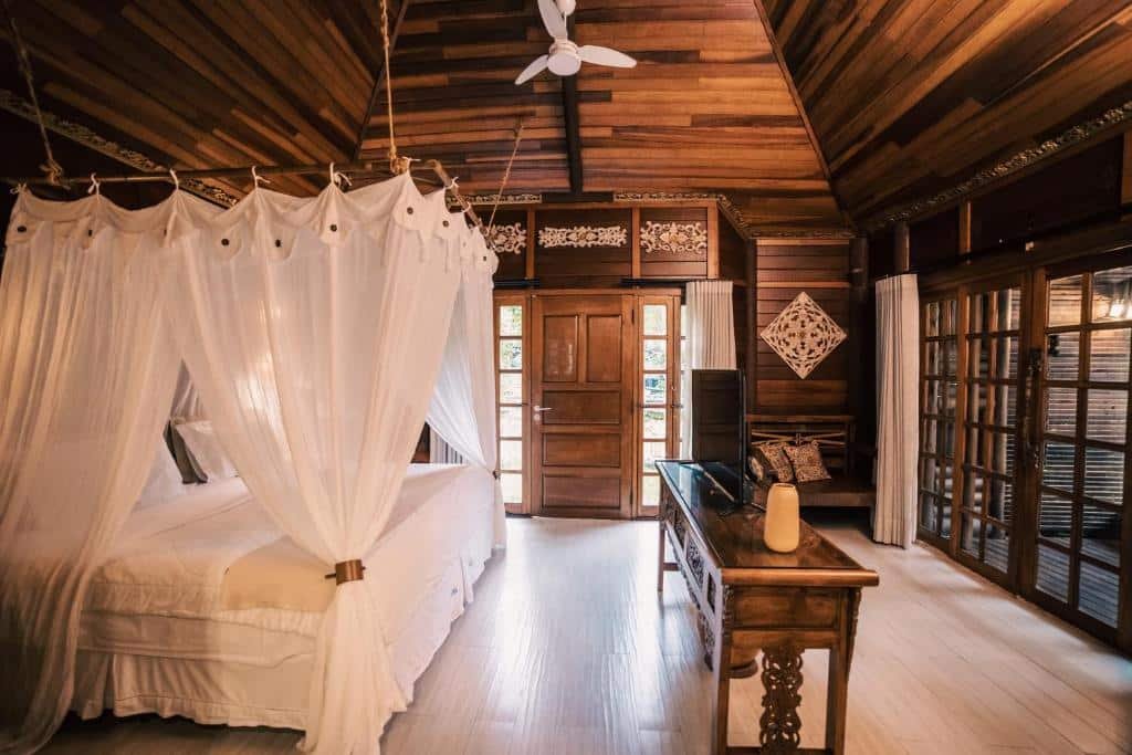 Quarto da Pousada Astral da Ilha. Uma cama de casal do lado esquerdo, no centro uma estante com televisão. No fundo a porta do quarto. Foto para ilustrar post sobre pousadas pet friendly no Paraná.