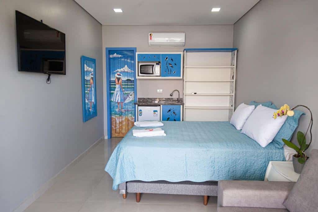 Quarto da Pousada Guaricana. Uma cama de casal e um sofá do lado direito, de frente uma televisão. No fundo a porta do banheiro e uma minicozinha. Foto para ilustrar post sobre pousadas pet friendly no Paraná.