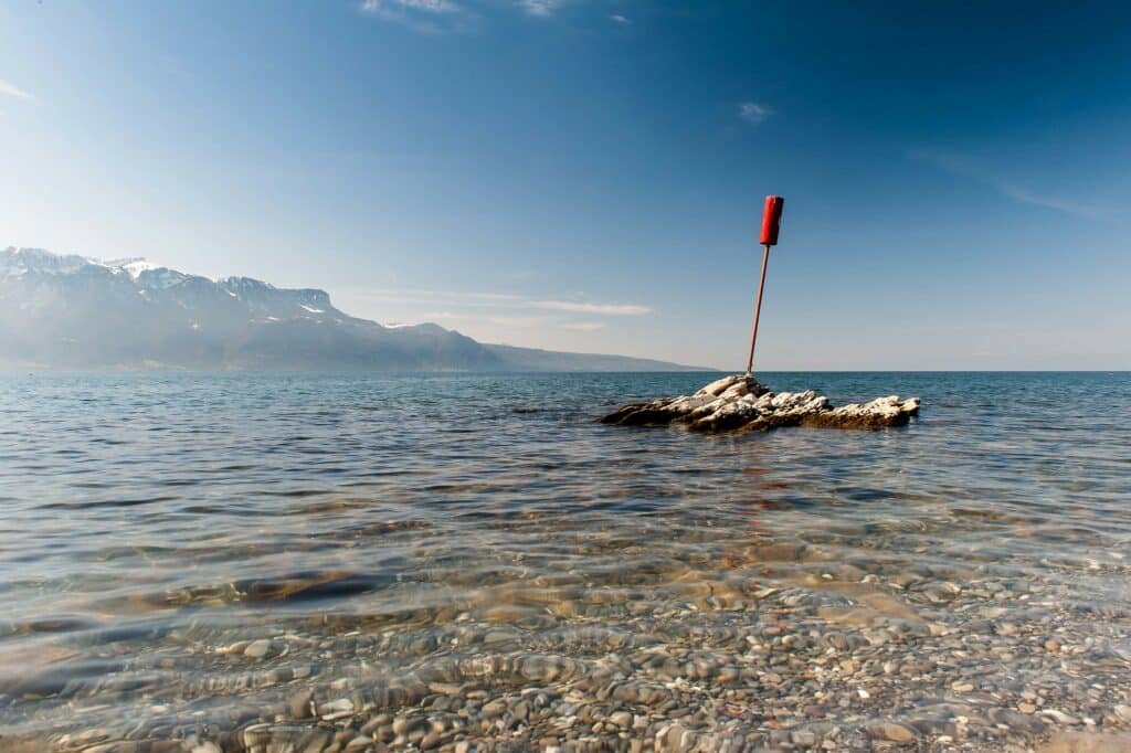 Imagem do La Plage de la Grotte durante o dia com o mar a frente e ao fundo do lado esquerdo montanhas.