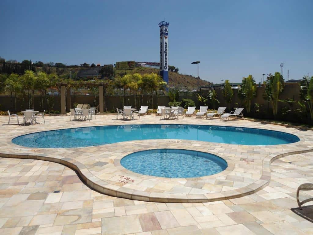 Piscina do Quality Hotel Jundiaí com cadeiras e mesas ao redor do local, para representar hotéis perto do Hopi Hari