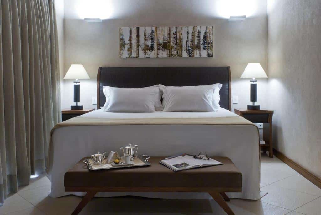 Quarto do Abayomi Hotel com uma cama de casal, duas mesinhas de cabeceira, uma varanda com cortinas, para representar resorts em Ilhabela