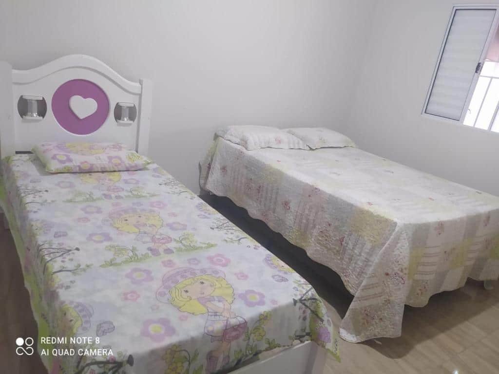 Quarto da "Casa acolhedora, bem aconchegante com piscina" com uma cama de casal e do lado uma cama de solteiro. Do lado da cama de casal tem uma janela de alumínio branca.