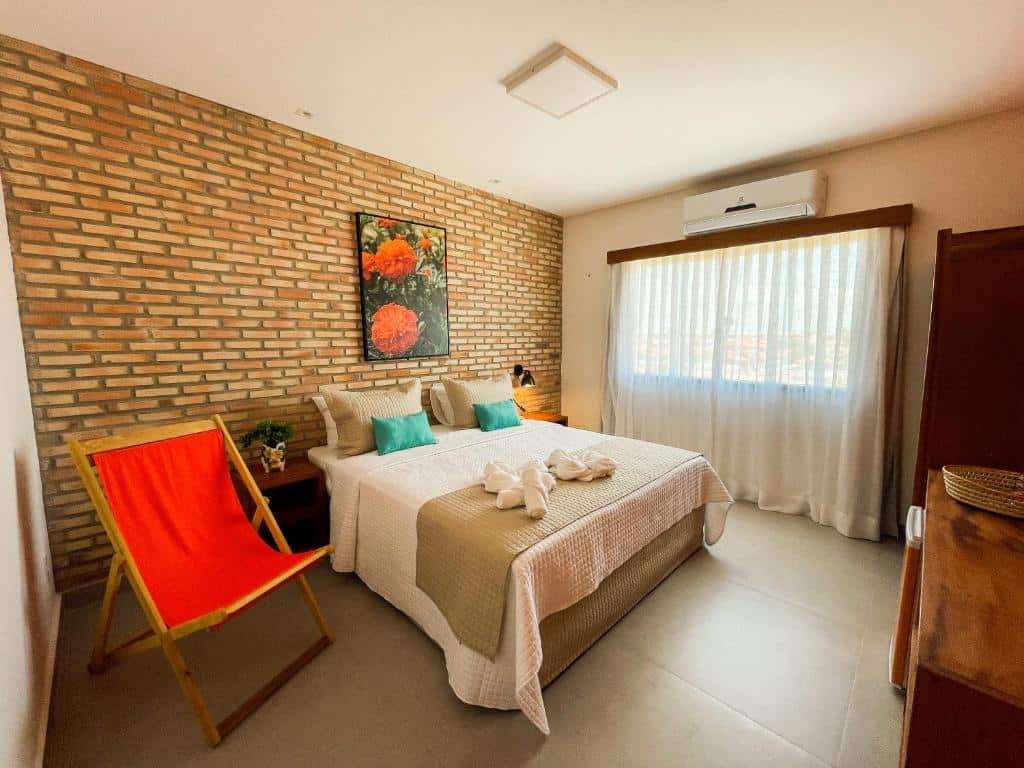 Quarto com cama ampla e cadeira na Pousada das Flores.