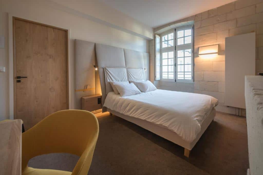 Quarto do Fontevraud L’Hôtel com cama de casal do lado esquerdo da imagem. Representa hotéis no Vale do Loire.