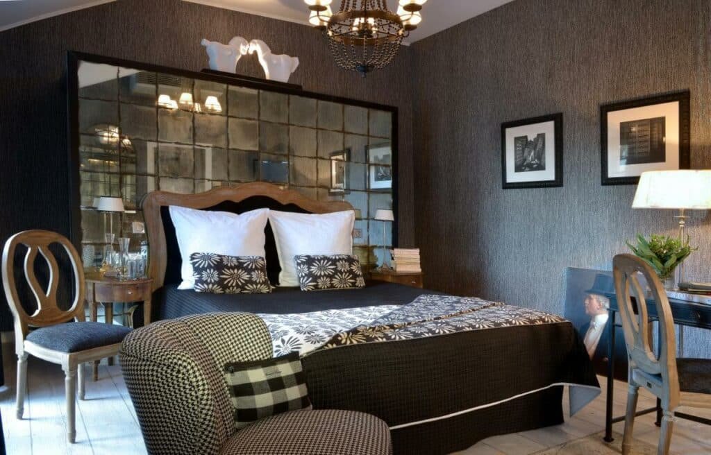 Quarto do Hôtel St Pierre com cama de casal do lado esquerdo da imagem no centro do quarto com uma cômoda em cada lado da cama, do lado direito da cama uma cadeira e no pé da cama uma poltrona. Representa hotéis no Vale do Loire.