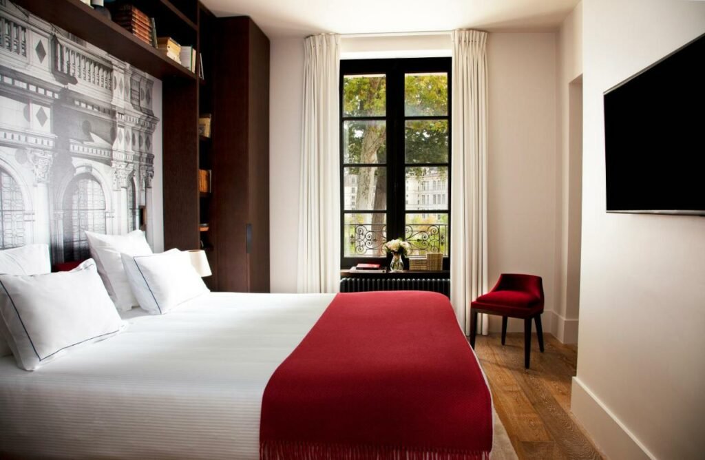 Quarto do Relais de Chambord – Small Luxury Hotels of the World com cama de casal do lado esquerdo da imagem em frente a cama uma TV presa na parede. Representa hotéis no Vale do Loire.