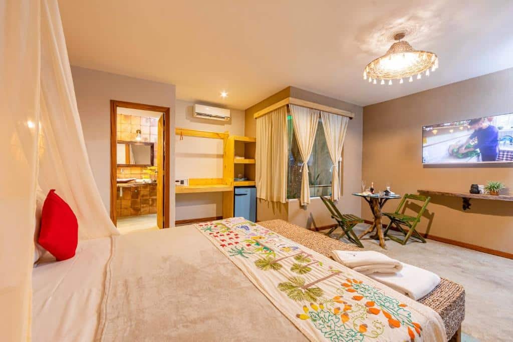 Quarto da Vila Parnaíba com cama ampla, TV e banheiro.