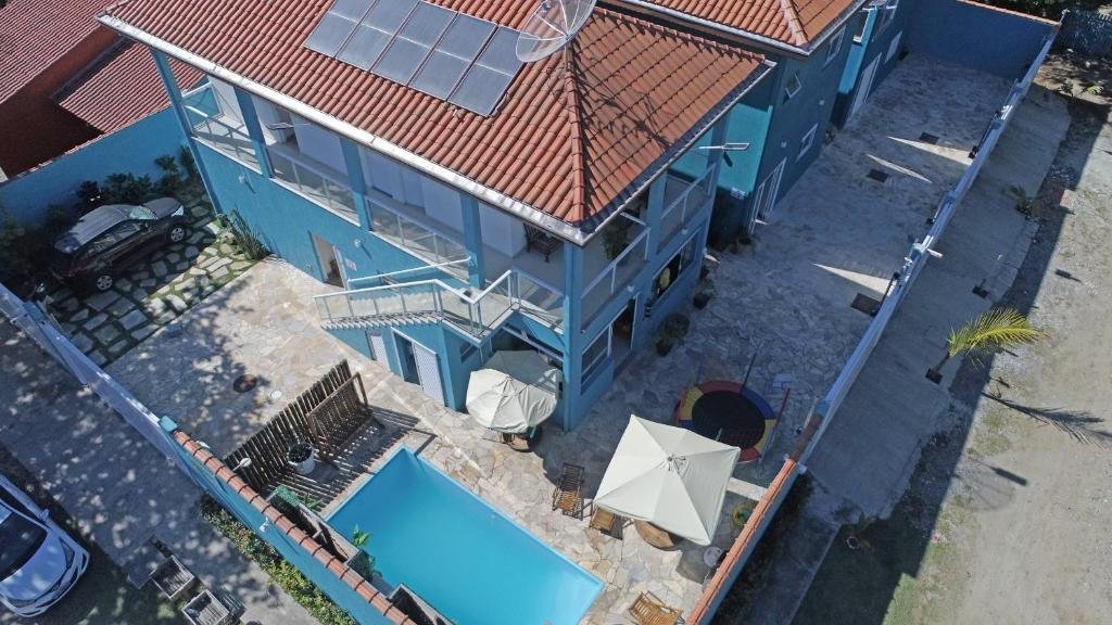 Vista aérea da pousada Residencial Águas de Bare que mostra a construção da pousada, uma piscina, um pula-pula, duas tendas e as garagens para os carros. Imagem ilustrando post Pousadas pet friendly no Litoral Norte de São Paulo.