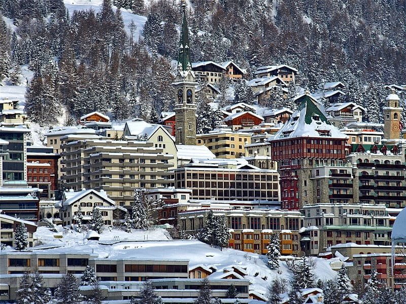 Imagem da cidade de Saint Moritz  durante o dia com prédios cobertos de neve.