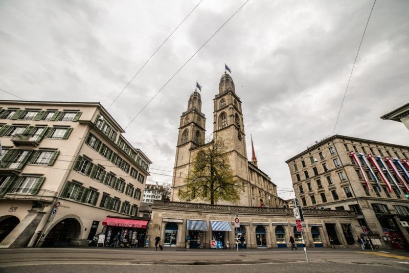 Imagem da igreja Grossmünster durante o dia com edifícios a frente e ao fundo a enorme igreja. Representa
o que fazer em Zurique.