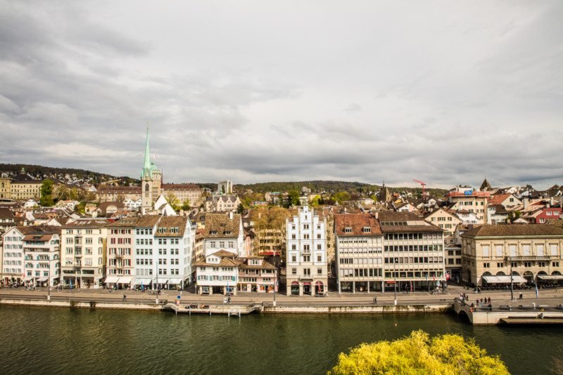 Imagem da região de Limmatquai durante o dia com rio a frente e ao fundo o bairro com vários prédios antigos. Representa o que fazer em Zurique.