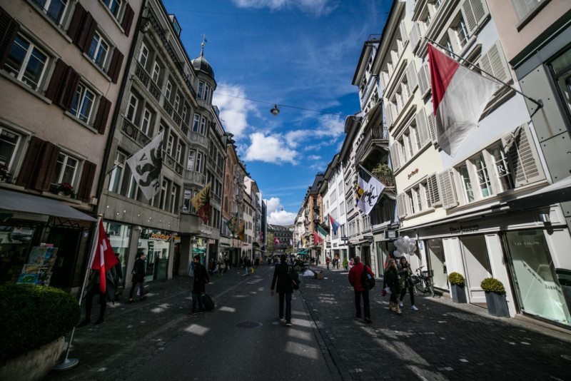 Imagem durante o dia da Rua Rennweg com perdestes na rua ao centro e em cada lado da imagem edifícios históricos.