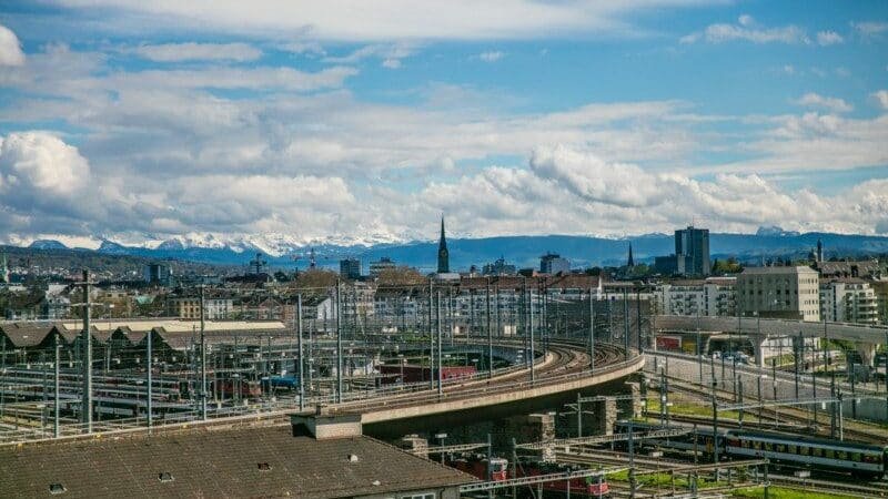 Imagem durante o dia da vista de Zurique da Loja Freitag com imagem de uma ponte no centro e ao fundo edifícios. Representa o que fazer em Zurique.
